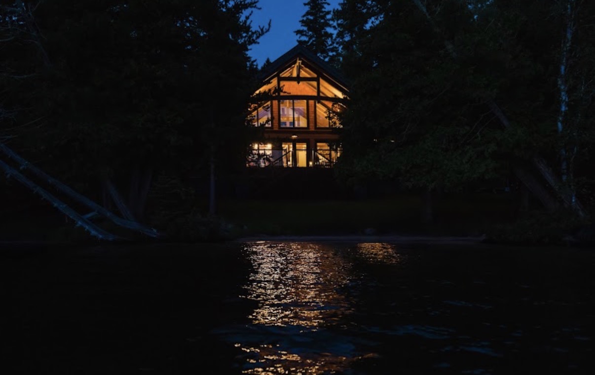 Lake-facing timber home lit up at night